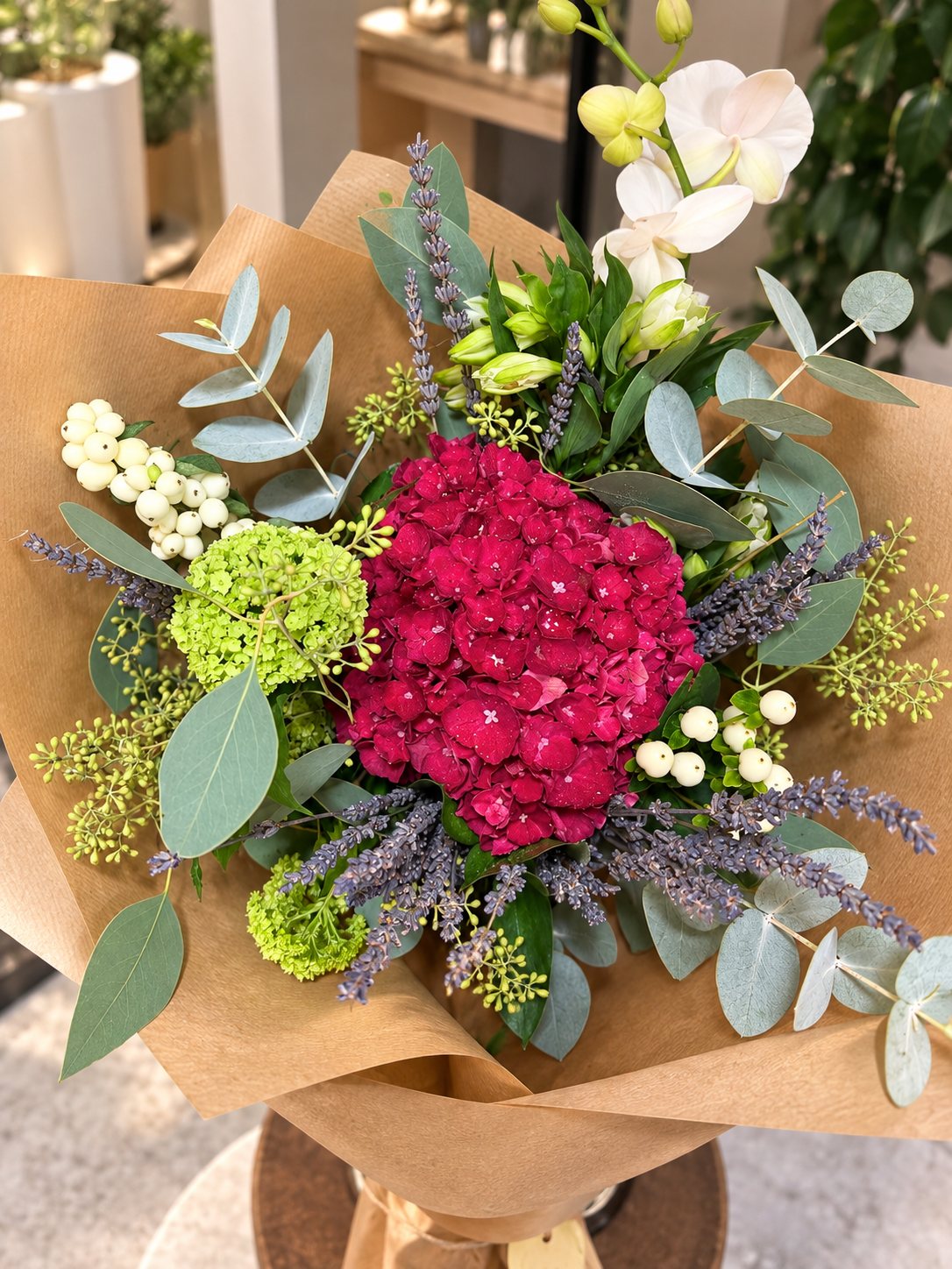 Hand-tied bouquet of magenta hydrangea, lavender, snowberry, viburnum and eucalyptus in kraft paper