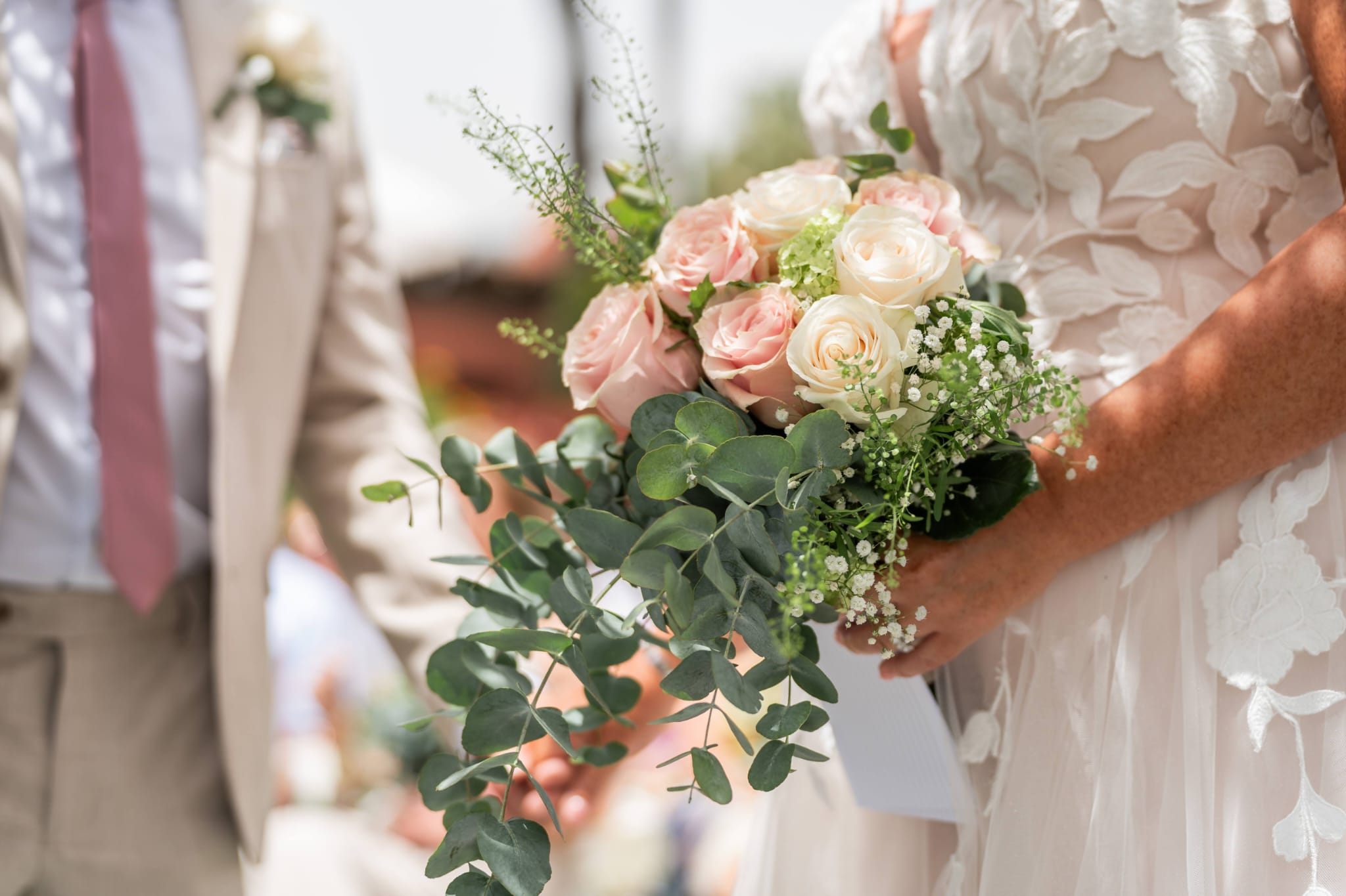 Bride holding a bouquet of blush and cream roses with trailing eucalyptus and gypsophila